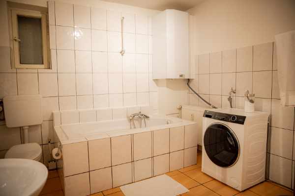 Badezimmer mit Badewanne und Waschmaschine - BONNYSTAY